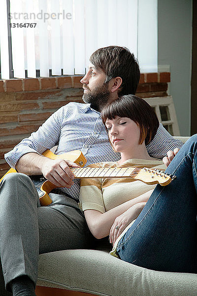 Junge Frau schläft neben einem Musiker auf dem Sofa
