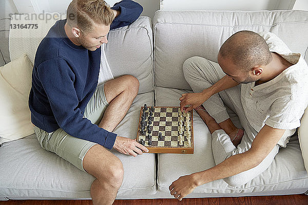 Hochwinkelansicht von Männern  die lächelnd auf dem Sofa sitzen und Schach spielen