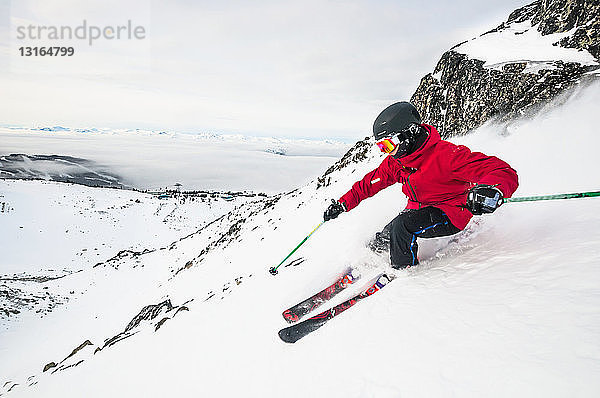 Seitenansicht eines jungen Mannes beim Skifahren auf einem verschneiten Berg  Whistler Blackcomb Skigebiet  Britisch-Kolumbien  Kanada