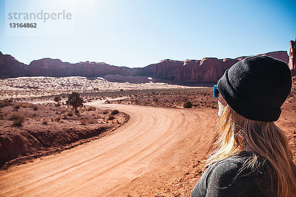 Mittelgroße erwachsene Frau  die auf eine unbefestigte Landstraße schaut  Monument Valley  Utah  USA