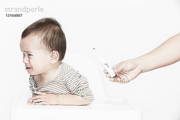 Baby weinender Junge  Digitalthermometer in der Hand haltend