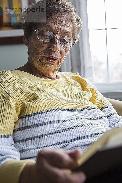 Ältere Frau liest zu Hause Buch