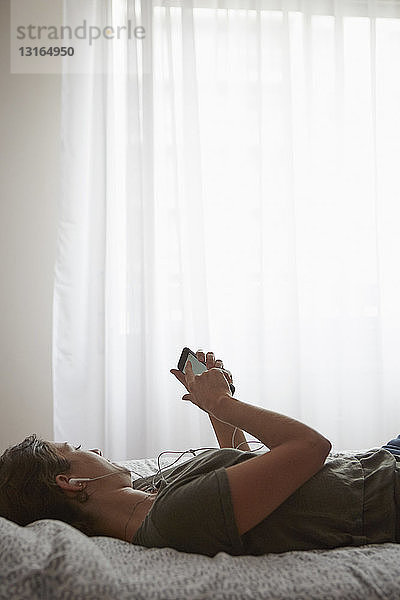 Frau benutzt Smartphone am Bett