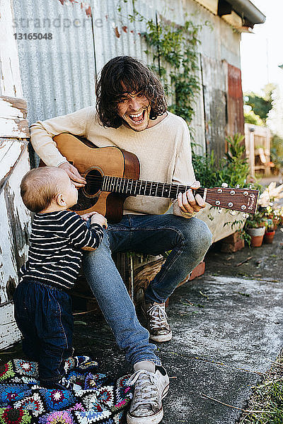 Vater unterhält Sohn mit Gitarre