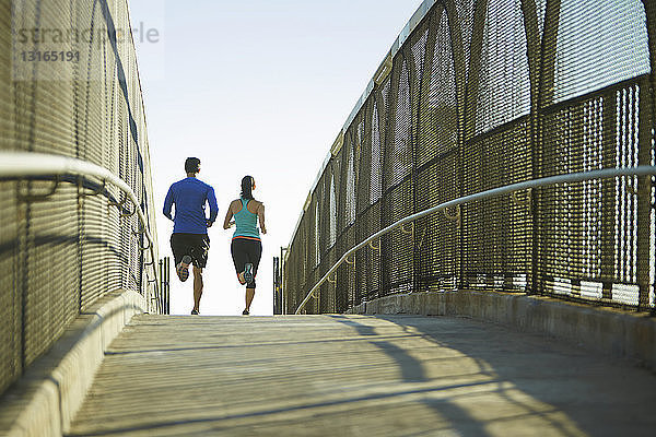 Mann und Frau laufen über die Brücke