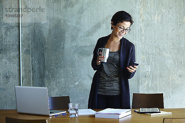 Junge Geschäftsfrau betrachtet Smartphone im Büro