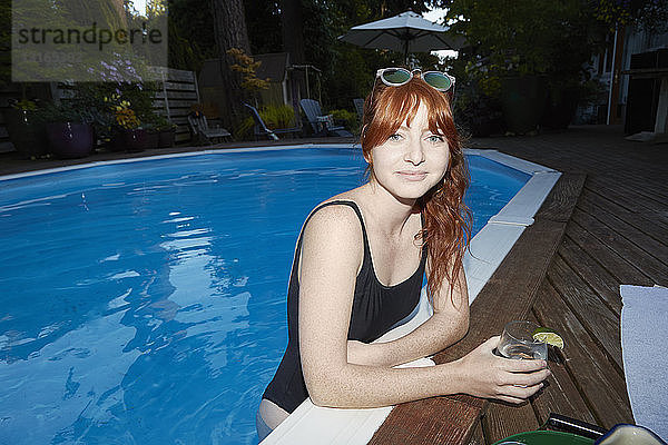 Porträt einer jungen Frau mit langen roten Haaren im Schwimmbad in der Abenddämmerung