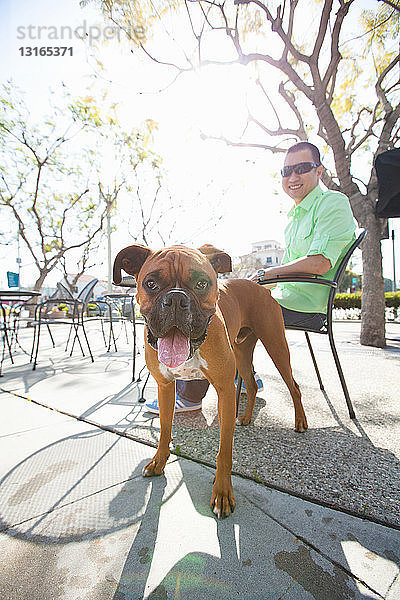 Mittelgroßer erwachsener Mann und sein Boxerhund im Parkcafé