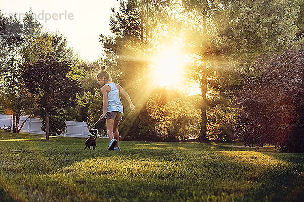 Rückansicht eines Mädchens im Park beim Laufen mit einem Boston-Terrier-Welpen
