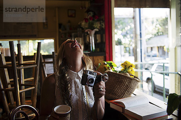 Junge Frau mit Kamera im Cafe