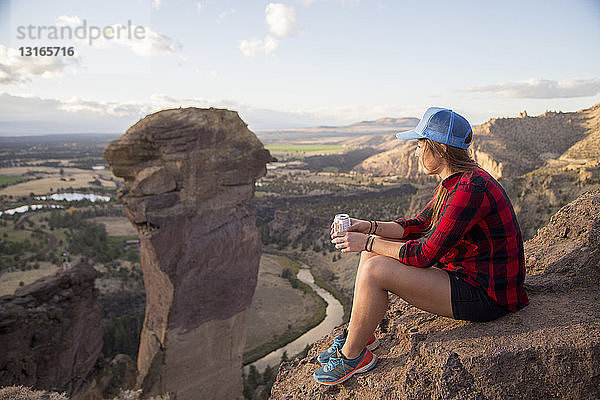 Junge Frau sitzt und betrachtet die Aussicht von der Spitze des Smith Rock  Oregon  USA