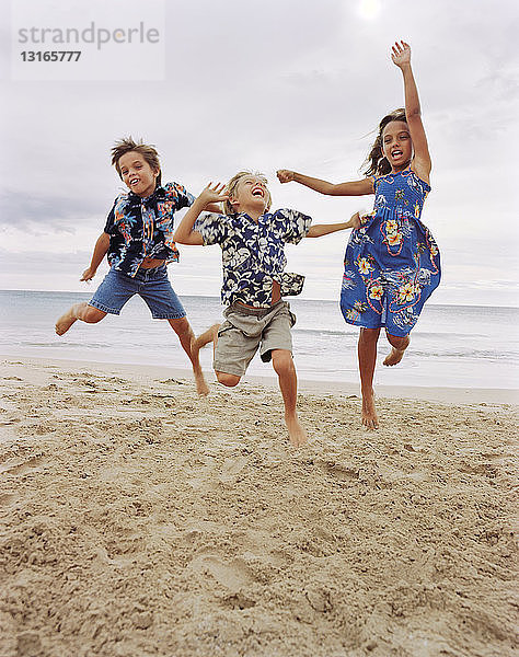 Kinder springen gemeinsam am Strand