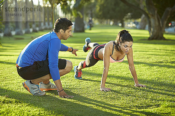 Persönlicher Trainer mit Frau bei einer Plankenübung