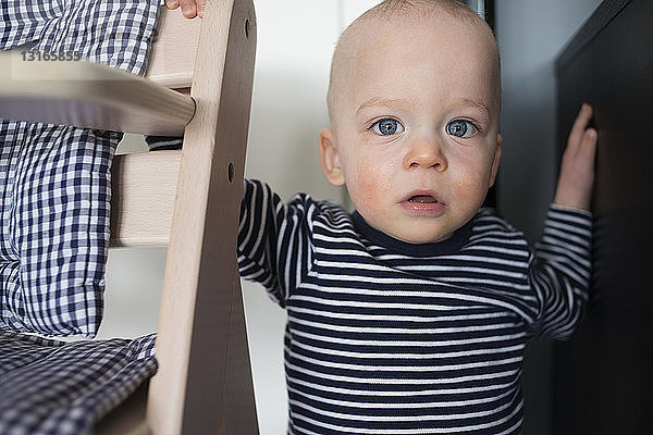 Porträt eines starren kleinen Jungen neben dem Hochstuhl