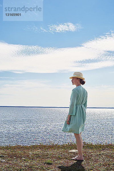 Mittelgroße erwachsene Frau im grünen Kleid am Meer stehend  Eggegrund  Schweden
