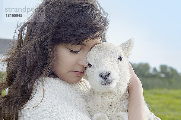 Bildnis einer jungen Frau auf dem Feld  die ein in eine Decke gewickeltes Lamm trägt