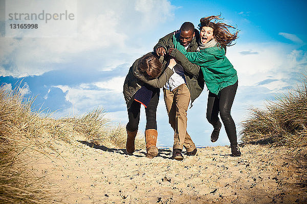 Junge erwachsene Freunde laufen in Sanddünen  Bournemouth  Dorset  UK