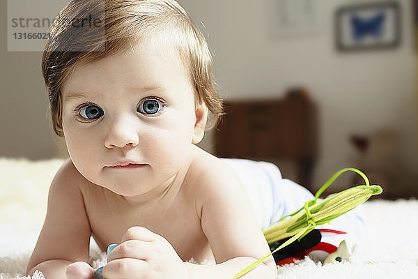 Porträt eines kleinen Jungen  der auf der Vorderseite liegt und in die Kamera schaut