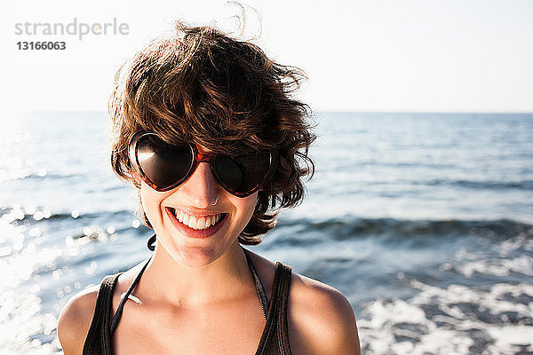 Lächelnde Frau mit Sonnenbrille am Strand
