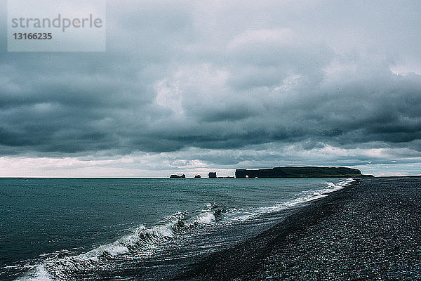 Ozeanwellen an der Küste unter dramatischem Himmel  Vik  Island