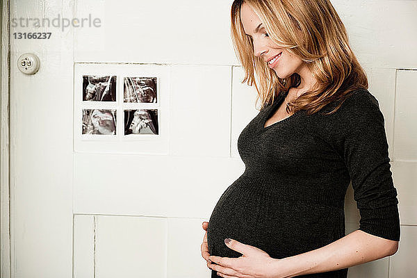 Schwangere Frau schaut auf den Bauch