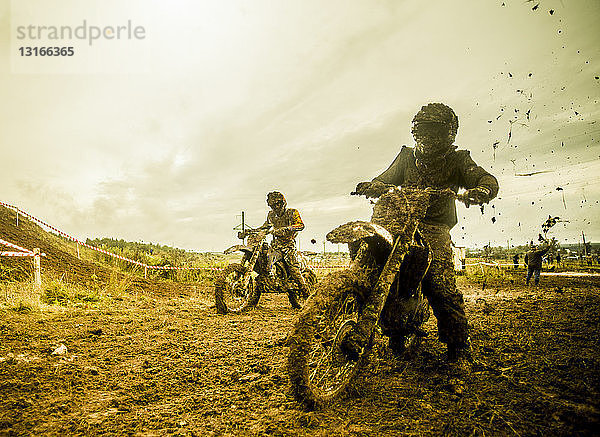 Zwei Jungen fahren Motorräder beim Motocross