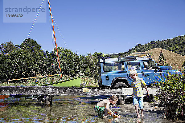 Jungen spielen mit ferngesteuertem Spielzeugboot auf dem Okareka-See  Neuseeland