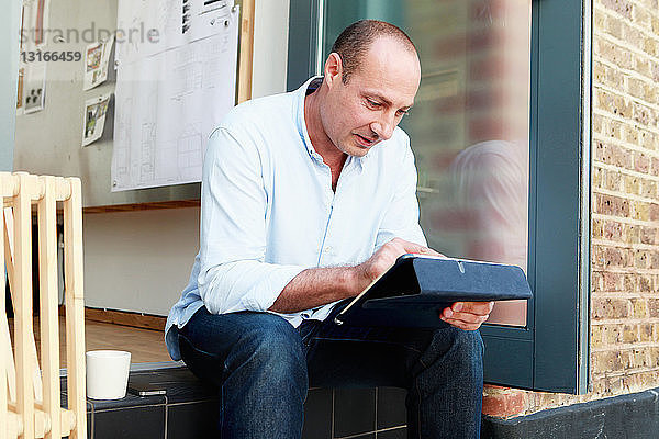 Männlicher Architekt benutzt Touchscreen auf digitalem Tablett auf Bürostufe