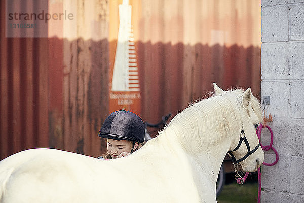 Mädchen pflegt Pony im Stall