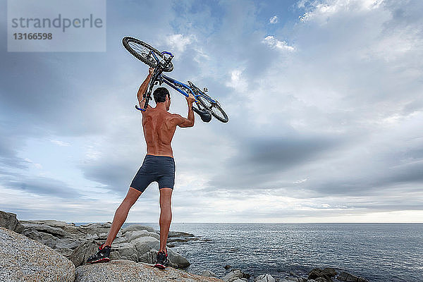 Mann hält Fahrrad auf Felsbrocken