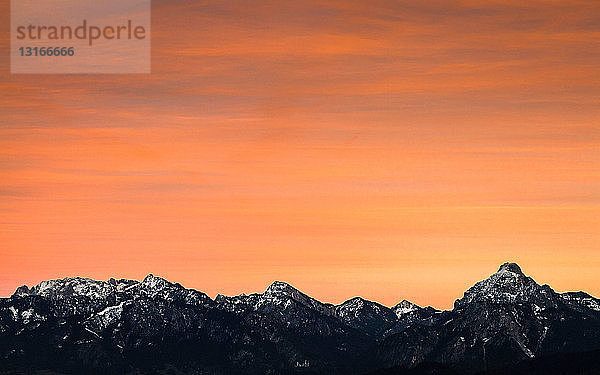 Bunter Himmel über verschneiten Bergen