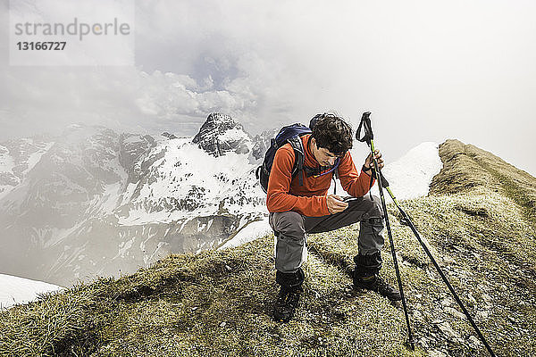 Junge männliche Bergwanderer texten auf Smartphones in den bayerischen Alpen  Oberstdorf  Bayern  Deutschland