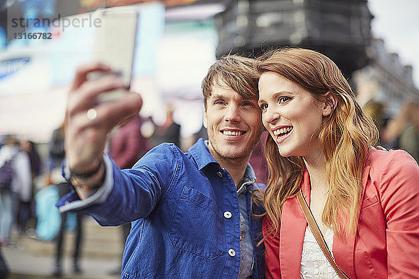 Touristisches Ehepaar beim Selfie auf dem Smartphone am Piccadilly Circus  London  Großbritannien