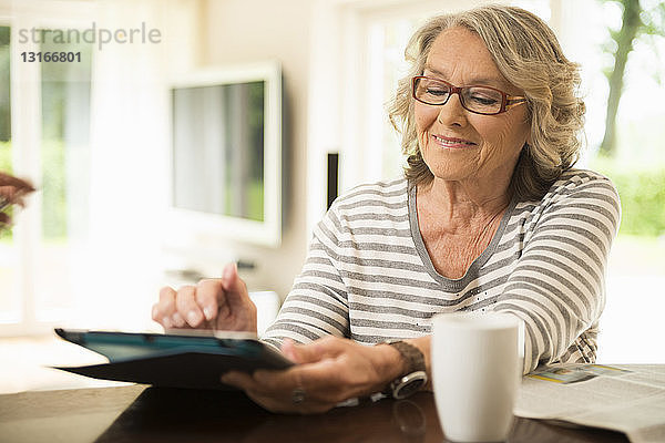 Ältere Frau liest mit digitalem Tablett