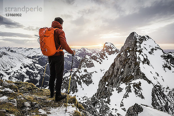 Rückansicht eines Wanderers mit Blick auf schneebedeckte Bergkette  Kellenspitze  Tannheimer Berge  Tirol  Österreich