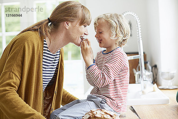 Junge Junge füttert Mutter mit einer süßen Leckerei