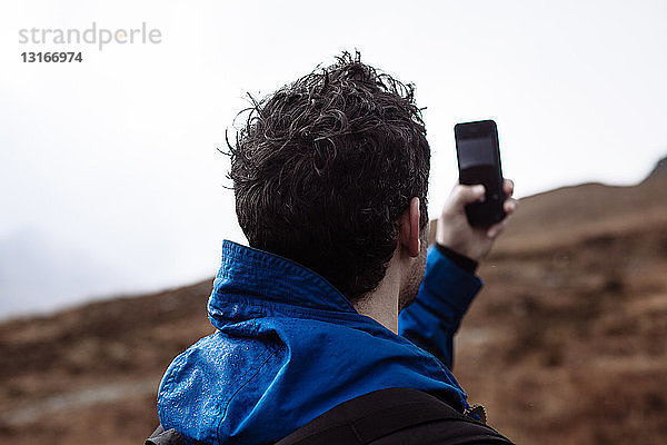 Mittelgroßer erwachsener Mann beim Fotografieren mit dem Telefon