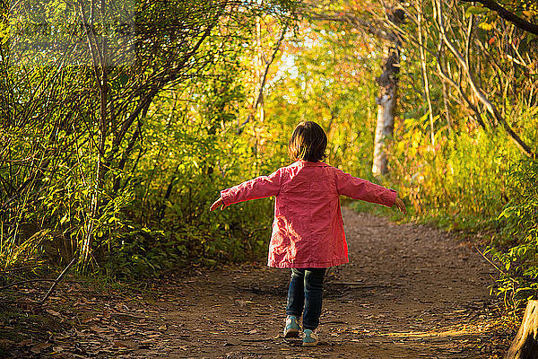 Glückliches weibliches Kleinkind spaziert durch den Herbstwald