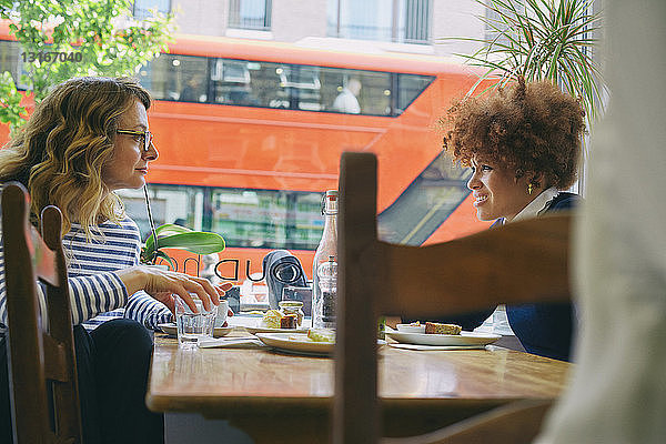Zwei Freundinnen essen zu Mittag und unterhalten sich in einem Café
