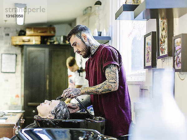 Friseur  der jungen Männern die Haare wäscht