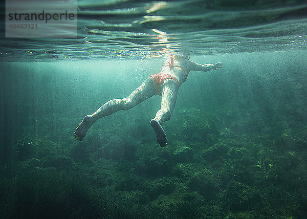 Unterwasseransicht einer mittleren erwachsenen Frau beim Schwimmen  Menorca  Balearen  Spanien