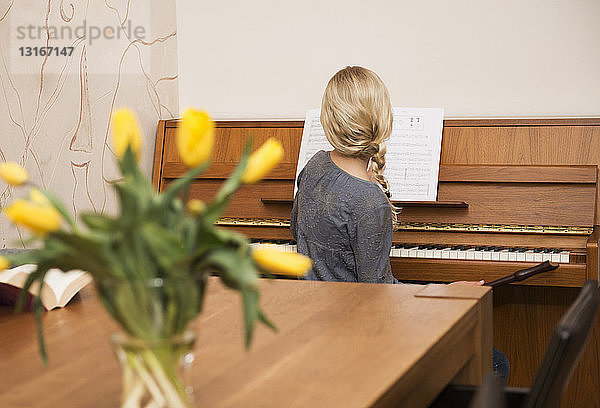 Rückansicht eines Mädchens am Klavier im Esszimmer