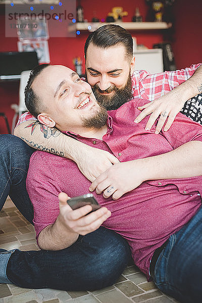 Schwules Paar benutzt Smartphone im Schlafzimmer