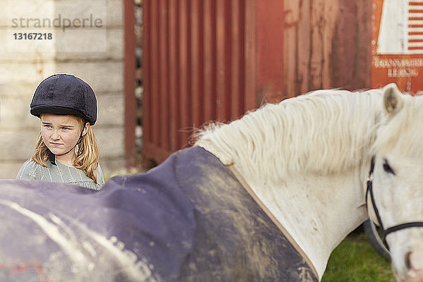 Mädchen und Pony schauen sich im Stall über die Schulter