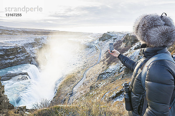 Frau fotografiert den Gullfoss-Wasserfall in der Schlucht des Flusses Hvita in Südwest-Island