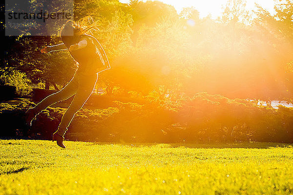 Junge Frau springt im Park in die Luft