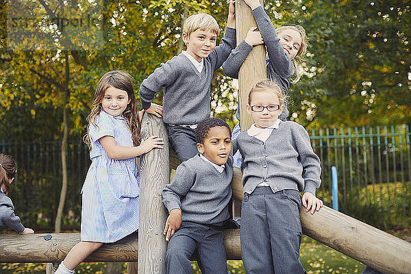 Porträt von Grundschulkindern auf dem Klettergerüst eines Spielplatzes