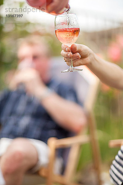 Frau schenkt Glas Wein im Freien ein