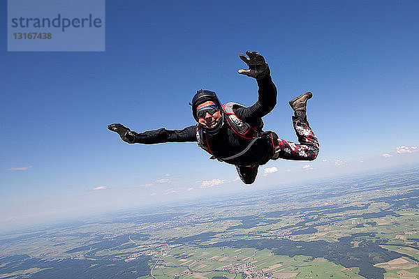 Mann beim Fallschirmspringen über ländlicher Landschaft