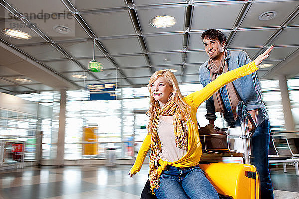 Pärchen spielt mit Gepäck im Flughafen